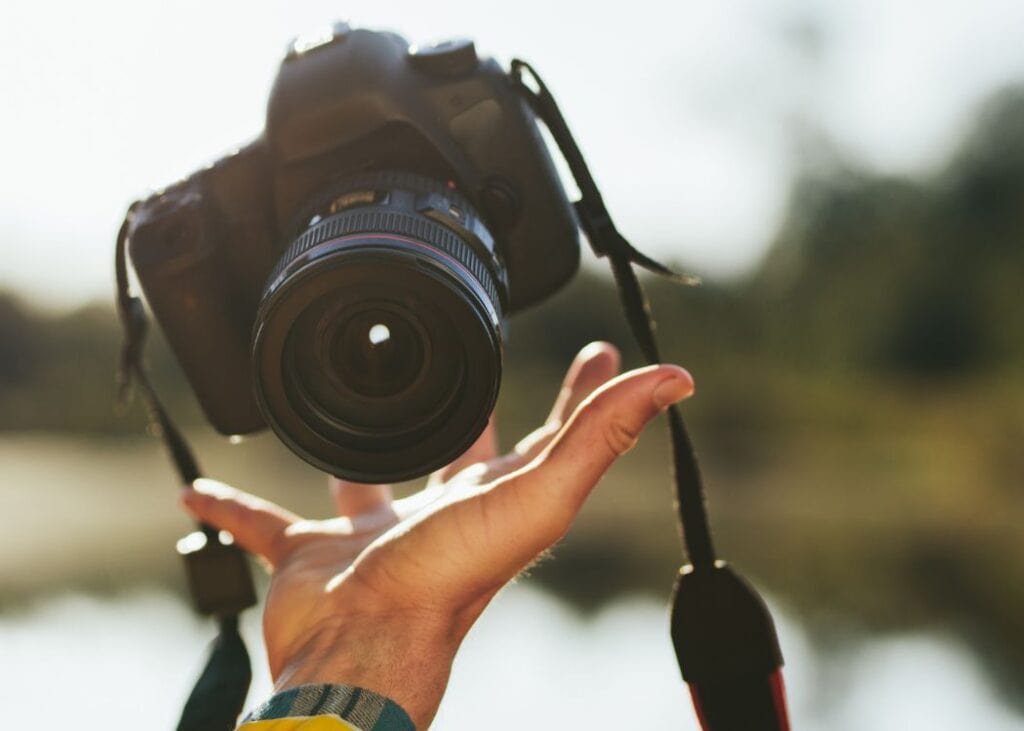 Person holding camera outdoors in sunlight.