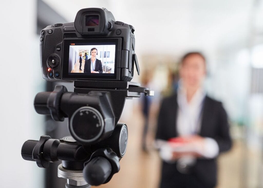 Camera recording a smiling businesswoman in office setting.