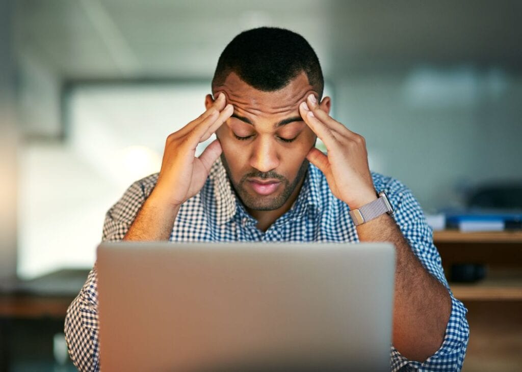 Man stressed working on laptop in office.