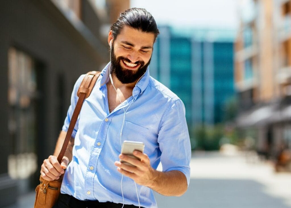 Smiling man using smartphone while walking in city.