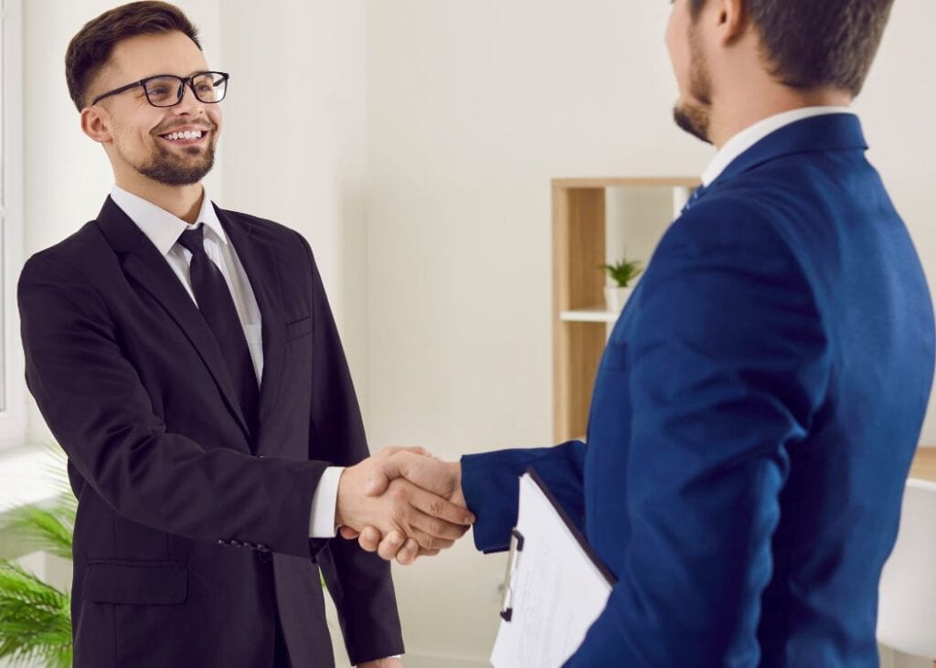 Two men in suits shaking hands in office.