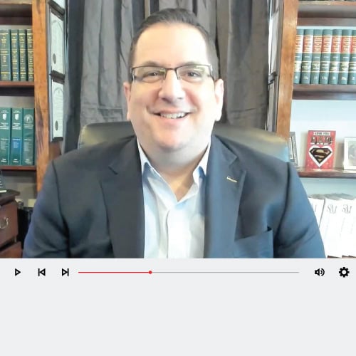 Smiling man in suit with library background.