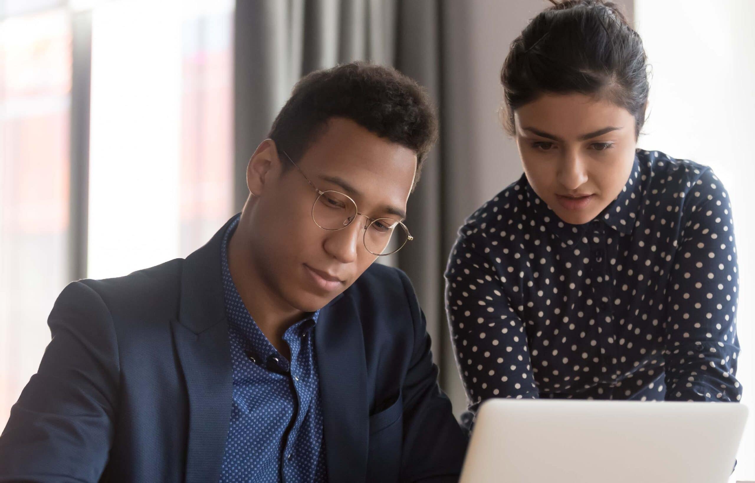 Two professionals collaborating on a laptop in office.