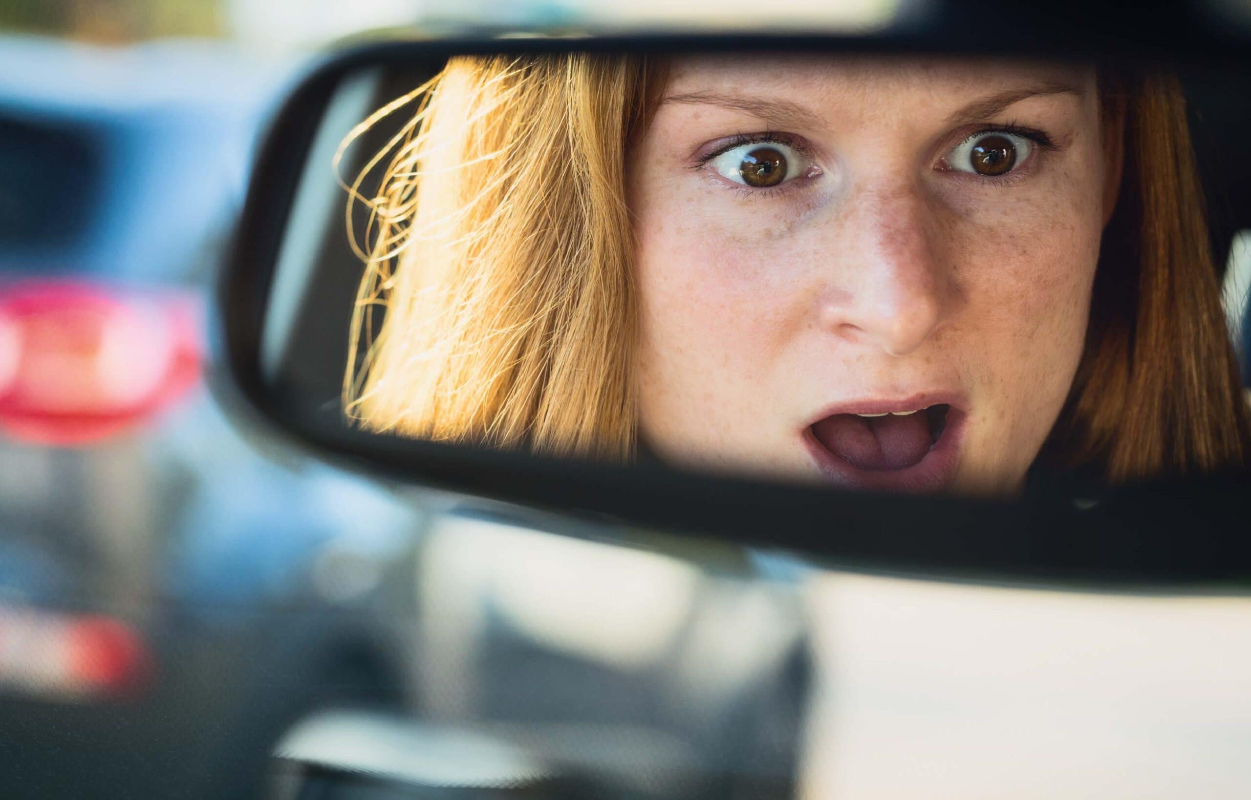 Woman surprised in car's rearview mirror.
