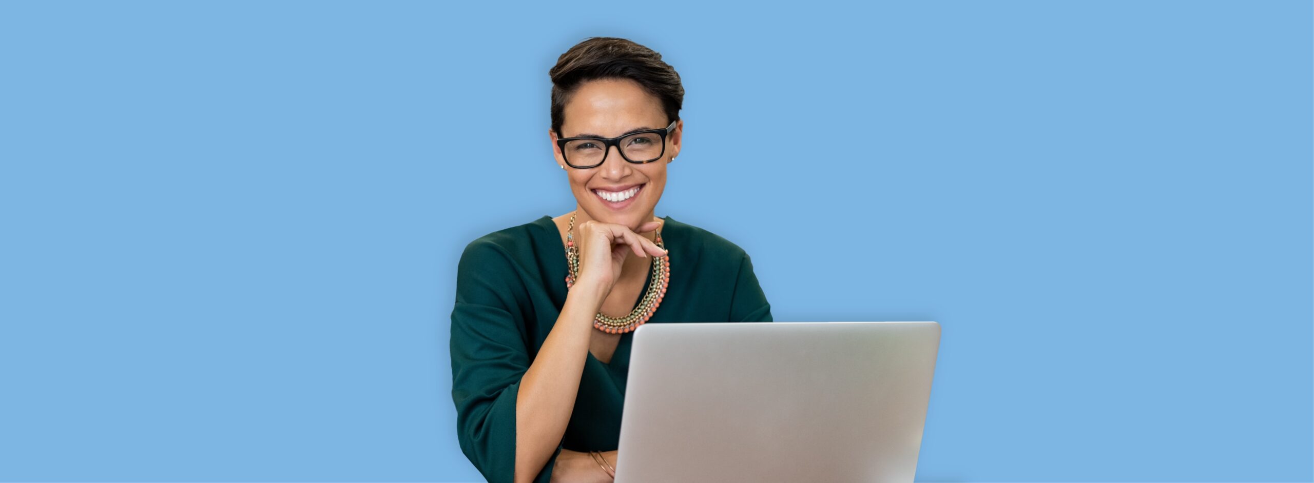 Smiling woman with glasses using laptop on blue background.