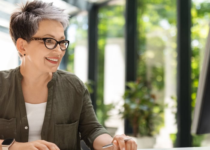 Mature woman smiling in a bright sunlit cafe.