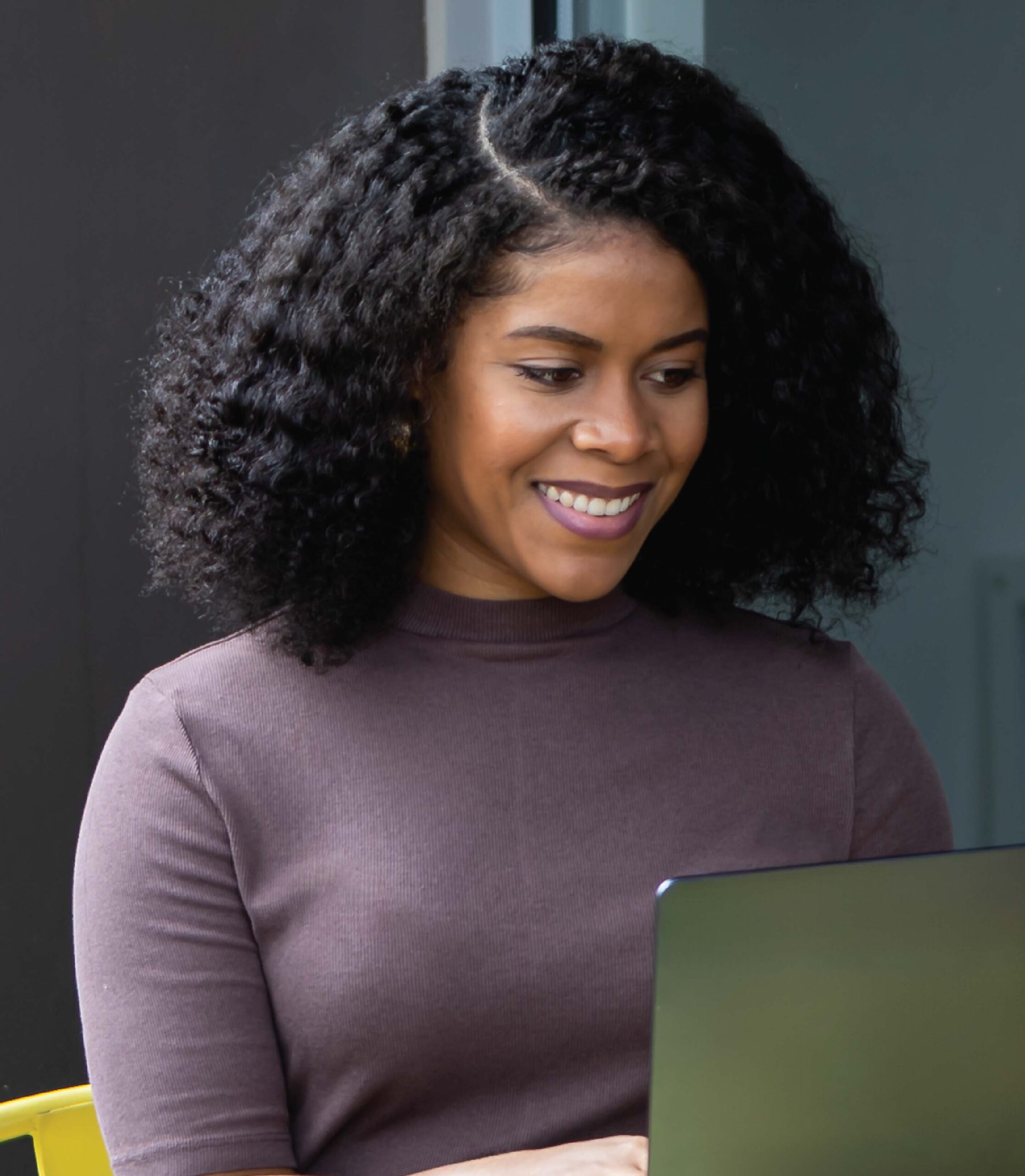 Smiling woman using laptop at modern workspace.