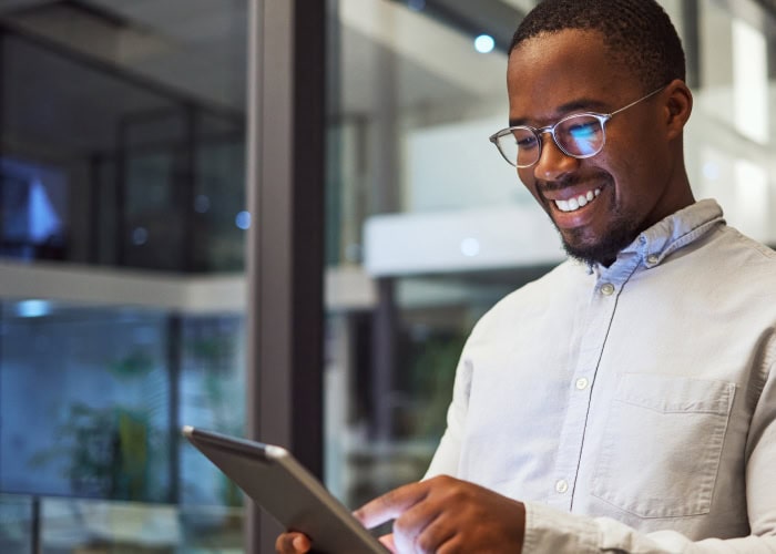 Man smiling while using tablet in modern office setting.