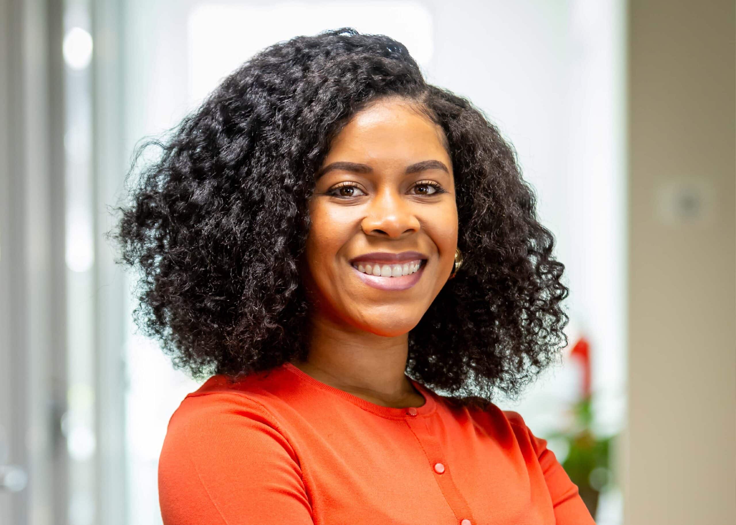 Smiling woman in red blouse, office background.