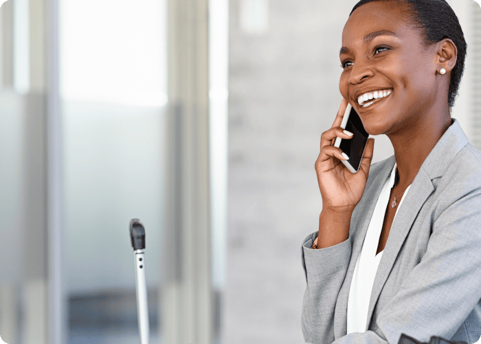 Businesswoman smiling while talking on smartphone in office.