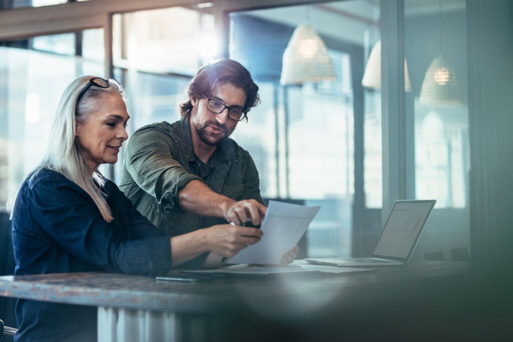 Two professionals collaborating over documents in a modern office.