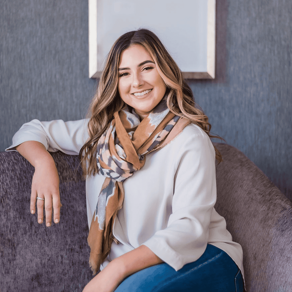 Smiling woman wearing scarf sitting on gray couch