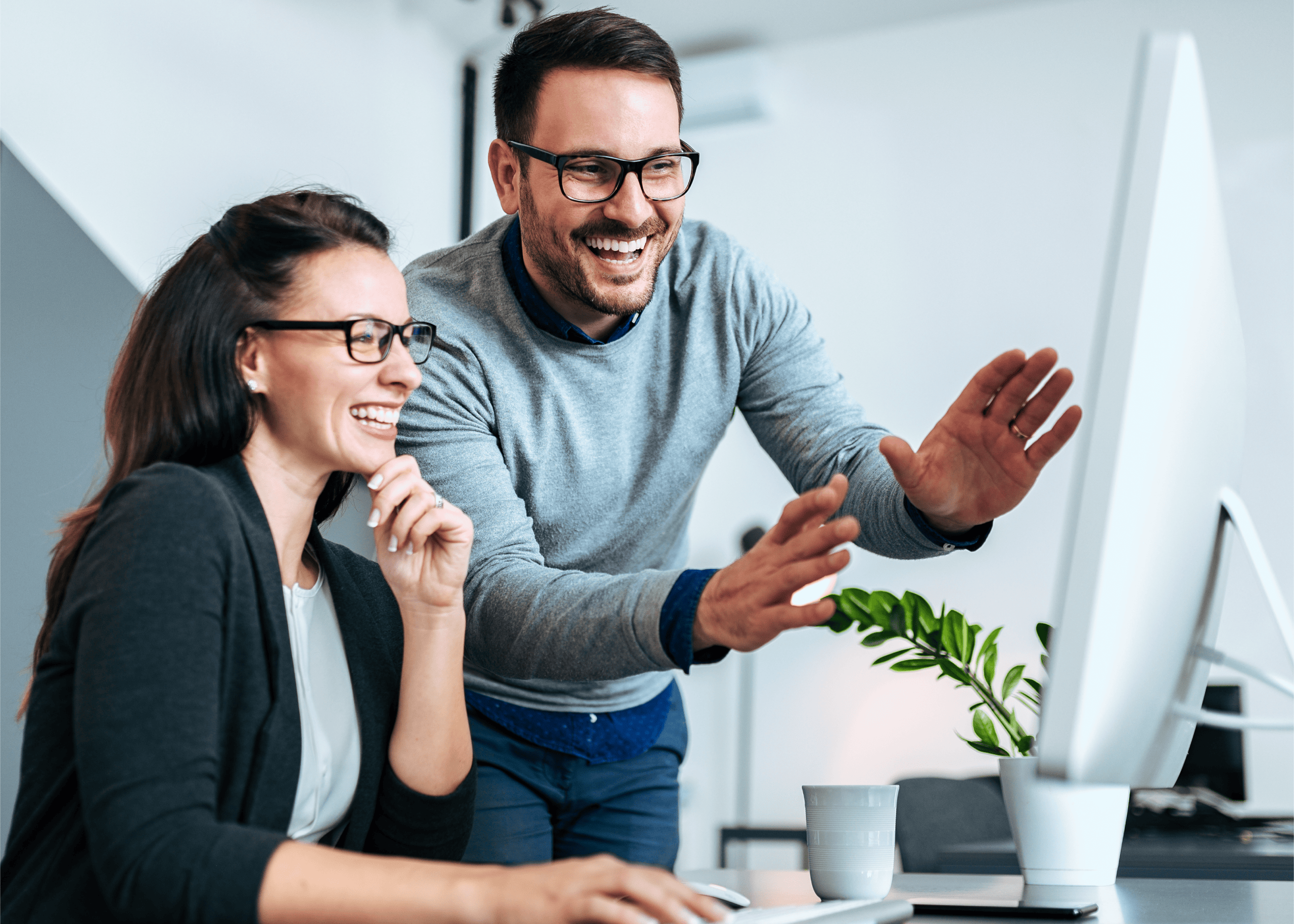 Two professionals happily collaborating on computer project