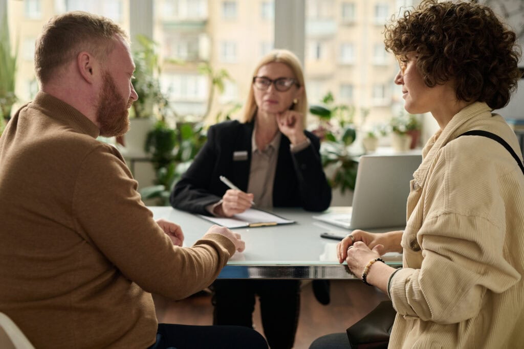 Three professionals in a meeting with paperwork and laptop