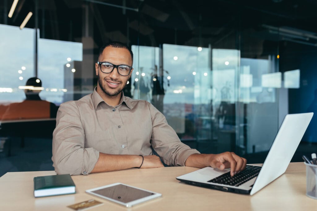 Smiling businessman working on laptop in modern office