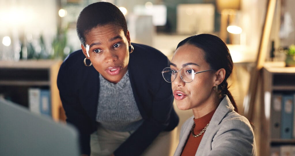 Two women collaborating at a computer in office