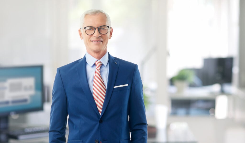 Confident businessman in blue suit smiling in office