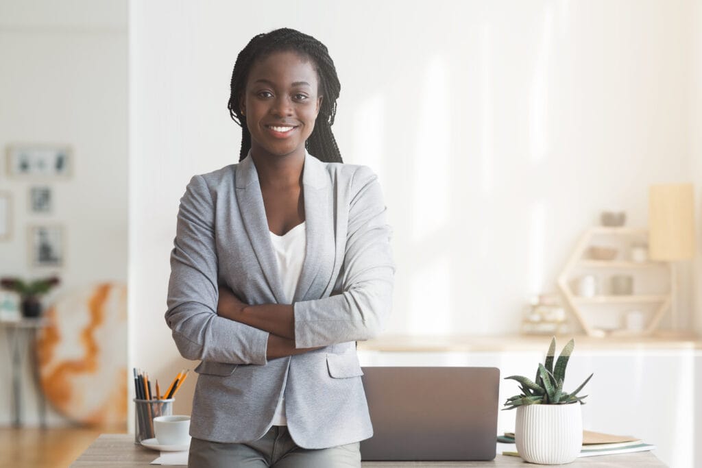 Confident businesswoman in office with laptop and plants