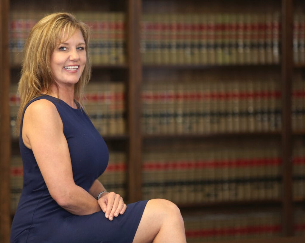 Smiling woman in blue dress sitting in law library