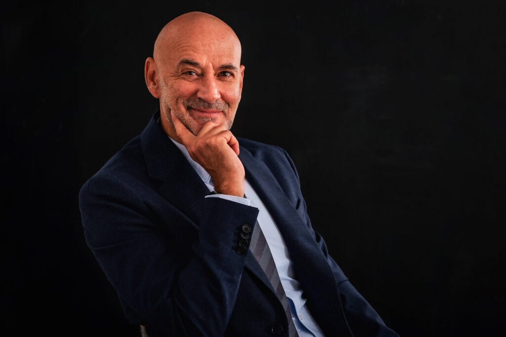 Smiling bald man in suit leaning chin on hand