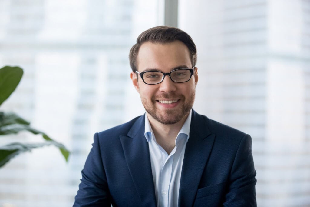 Smiling businessman in glasses and blue suit.