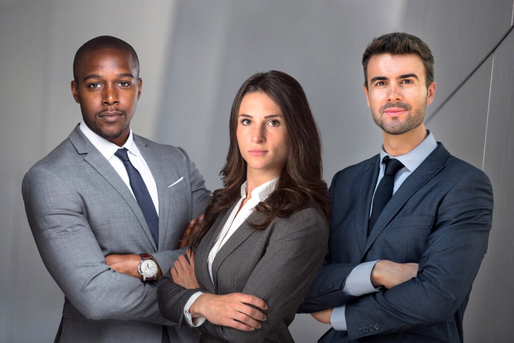 Three professionals in suits posing confidently