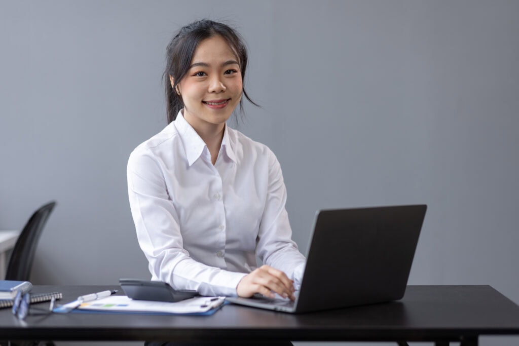 Smiling woman working on laptop at office desk