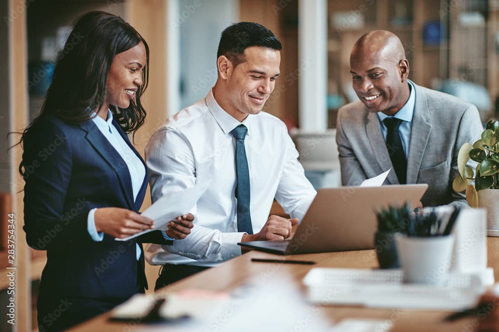 Diverse business team discussing project at laptop in office