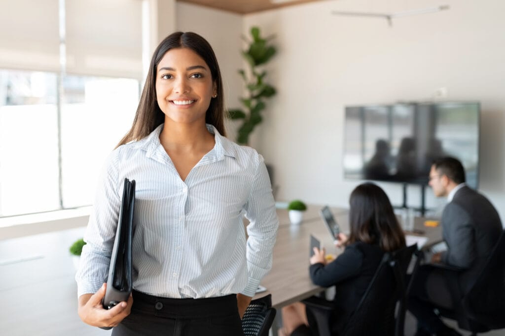 Professional woman smiling in office with coworkers