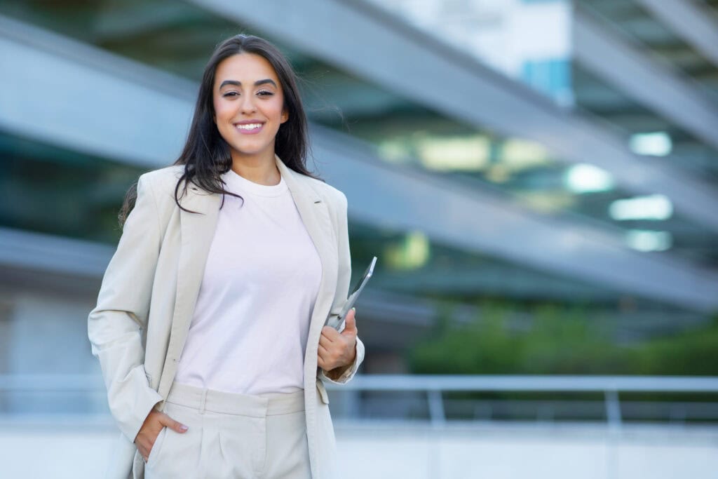 Confident woman with tablet outside modern building