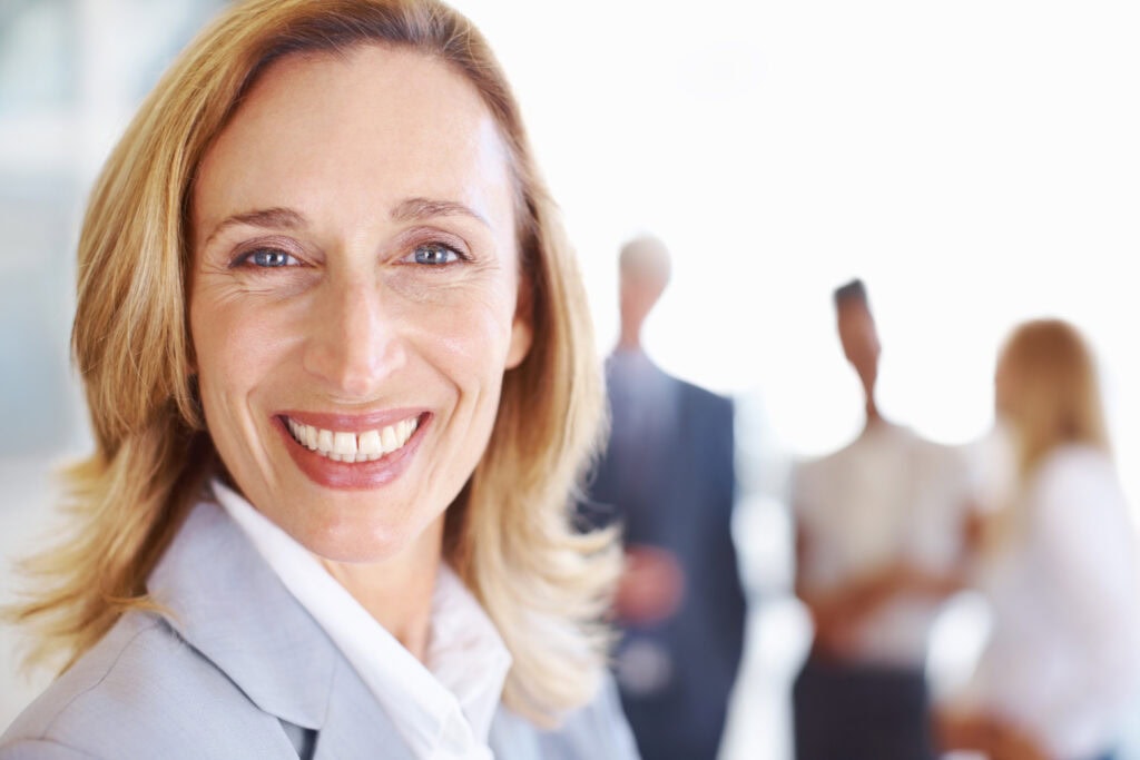 Smiling businesswoman with colleagues in background