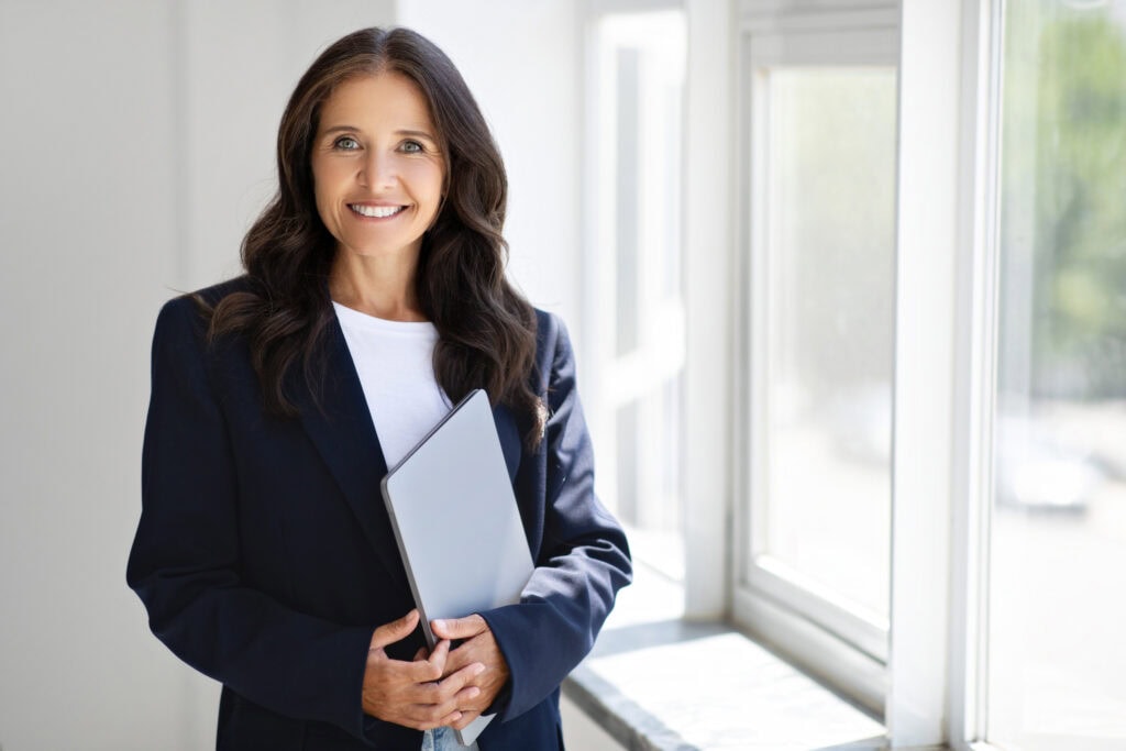 Smiling businesswoman with laptop by bright window
