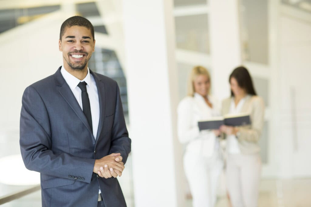Smiling businessman in office lobby with colleagues