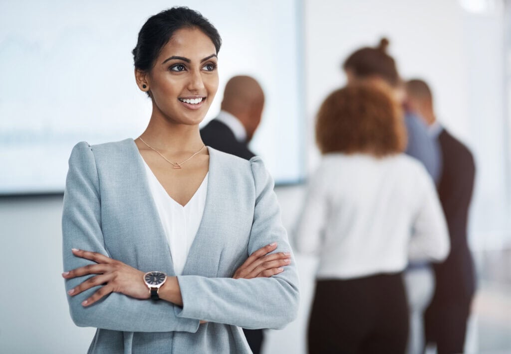 Confident businesswoman with colleagues in background
