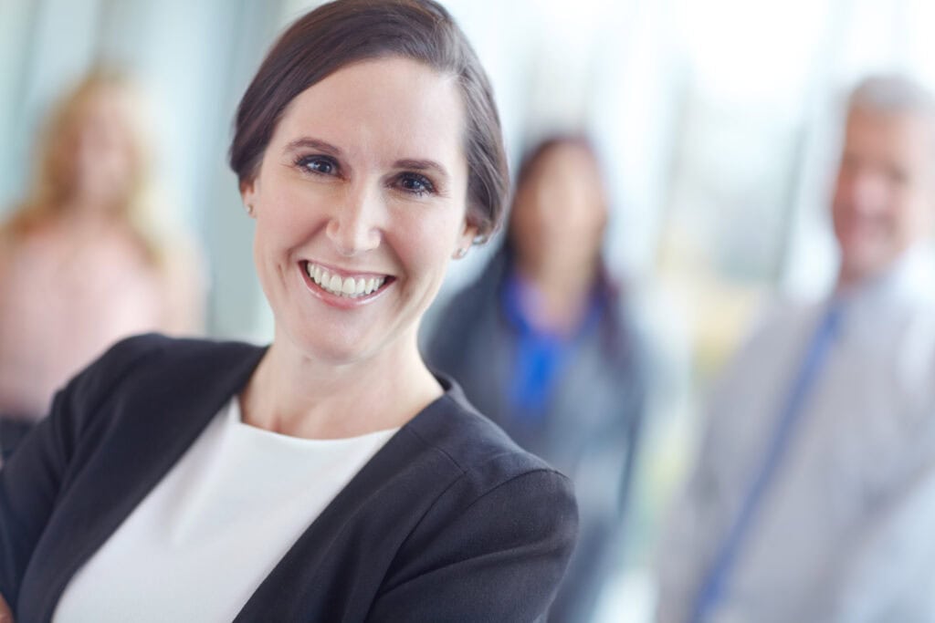 Smiling businesswoman with team in background