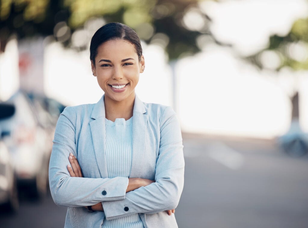 Confident businesswoman smiling outdoors with arms crossed