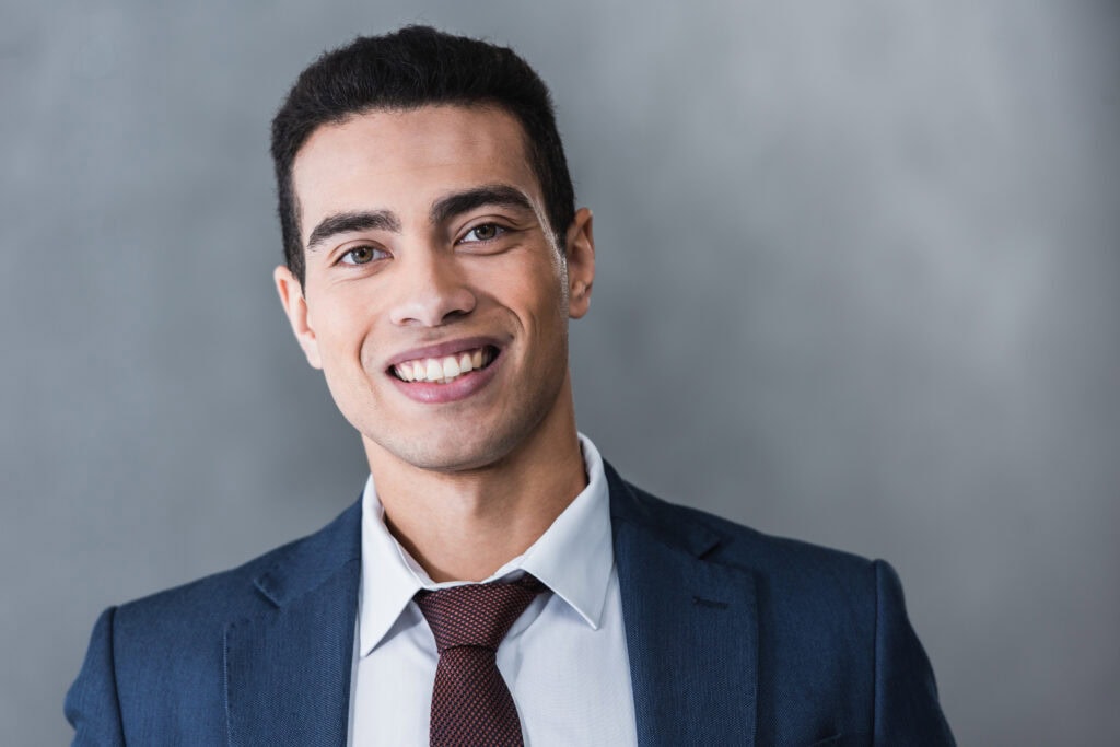 Smiling businessman in suit against gray background
