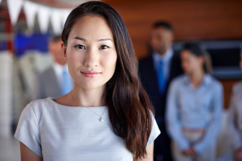 Confident Asian businesswoman with team in background