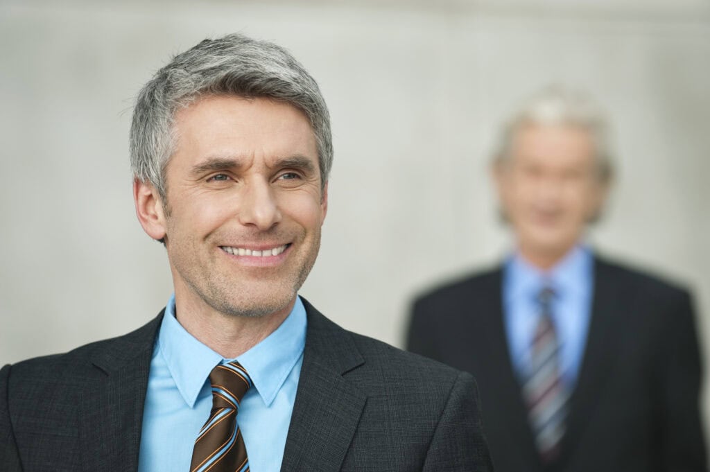 Smiling businessman with colleague in background