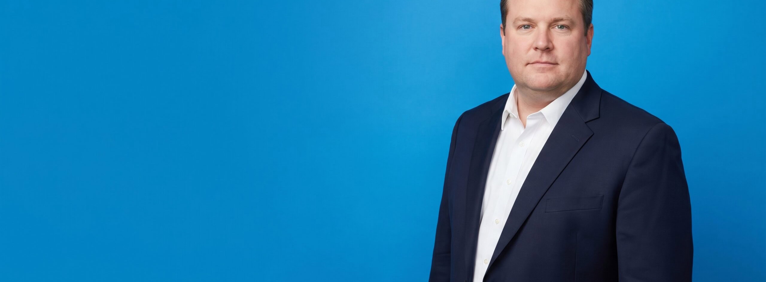 White male law-firm owner in his late 40s, plus-size build, navy suit jacket and white shirt, on a blue studio background — Why Referrals Are Not Enough Anymore: What the Data Says About How Legal Clients Find Attorneys.