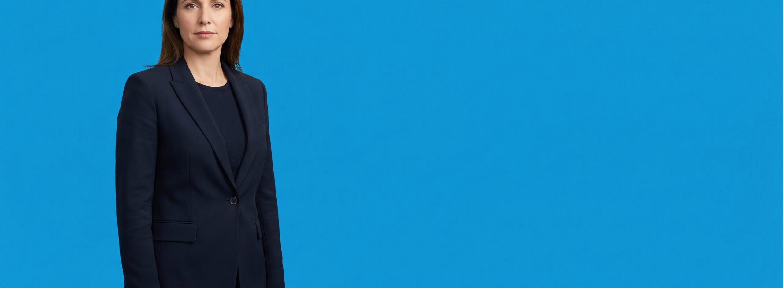 White woman professional in her early 40s, average build, dark navy blazer and dark top, on a blue studio background — Why Law Firm Intake Is a Marketing Problem (Not an Operations Problem).