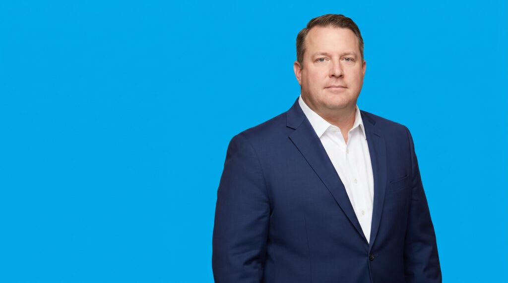 White male law-firm owner in his late 40s, plus-size build, navy suit jacket and white shirt, on a blue studio background — Why Referrals Are Not Enough Anymore: What the Data Says About How Legal Clients Find Attorneys.